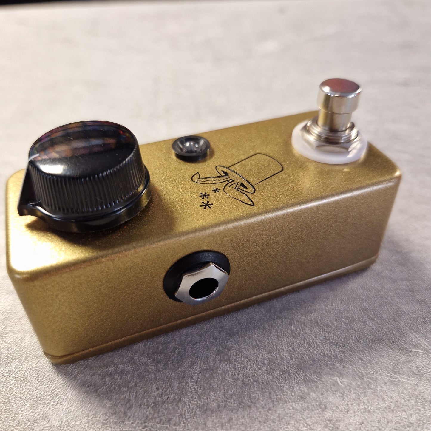 Pre-Owned JHS Gold guitar effects pedal with knobs and switch on a gray surface