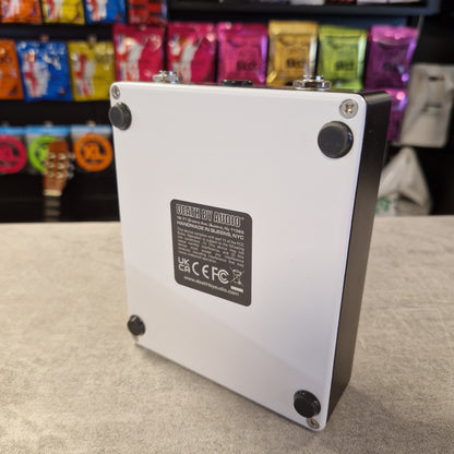 Pre-Owned Death By Audio Metal box with a label on a textured surface, with colorful items in the background