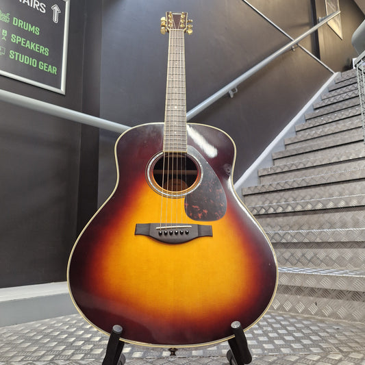 Pre-Owned Yamaha LL6 ARE Acoustic guitar leaning against a wall with a textured surface