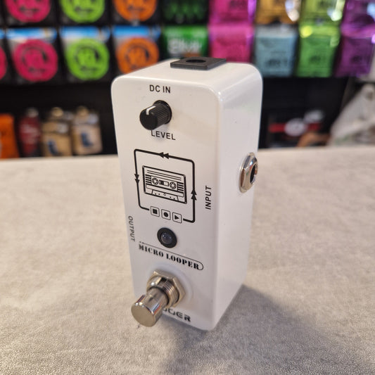 Pre-Owned Mooer Micro Looper White guitar effects pedal on a beige surface with colorful boxes in the background