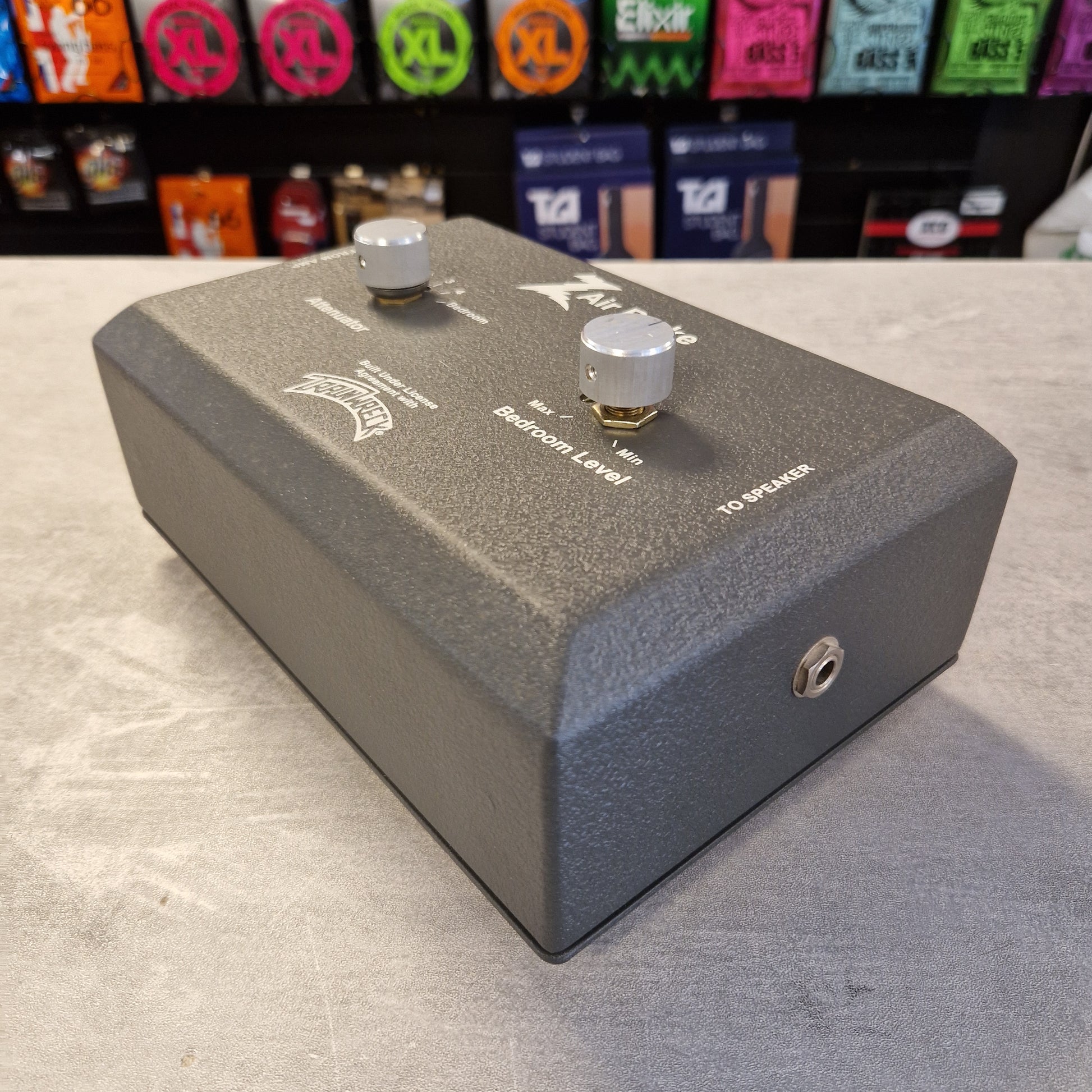 Pre-Owned Dr. Z Trainwreck Guitar effects pedal on a concrete surface with a rack of additional pedals in the background.