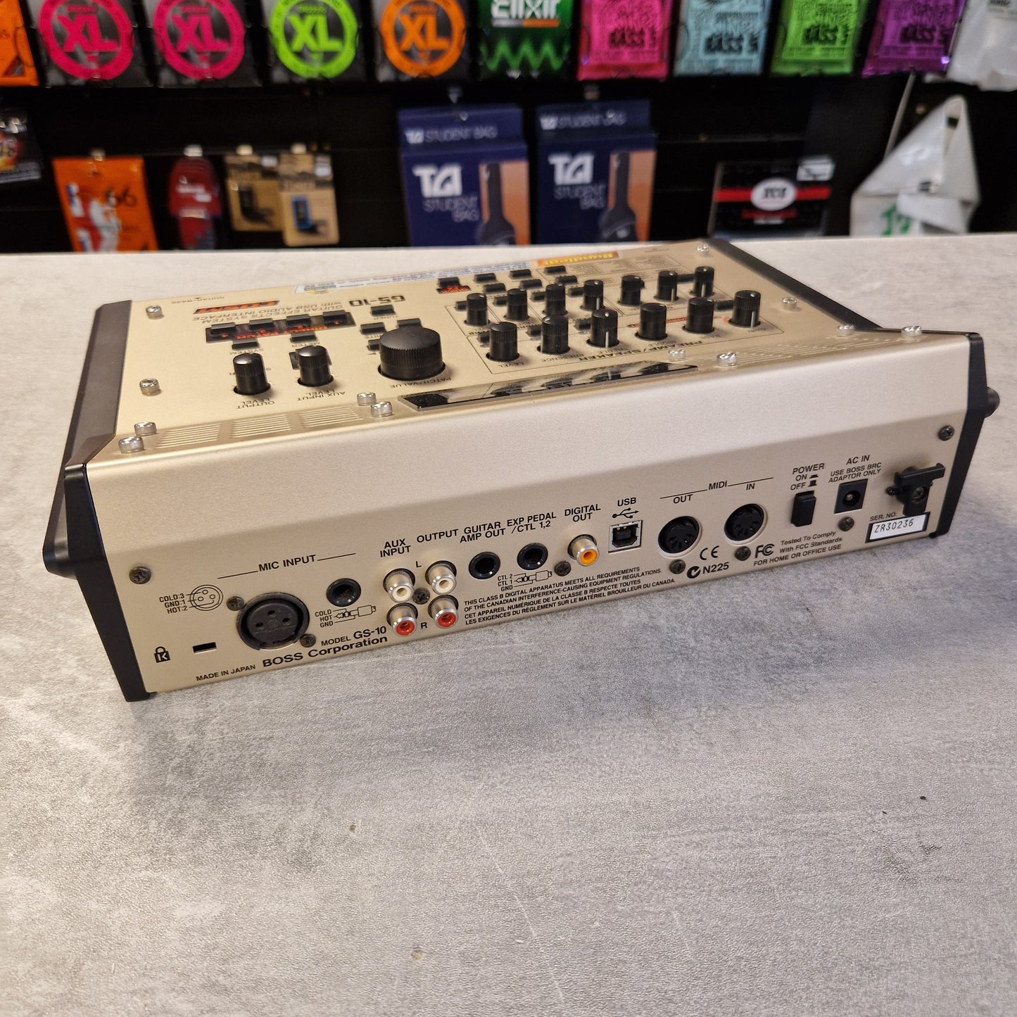 Pre-Owned Boss GS-10 Guitar effects pedal on a gray surface with colorful pedals in the background