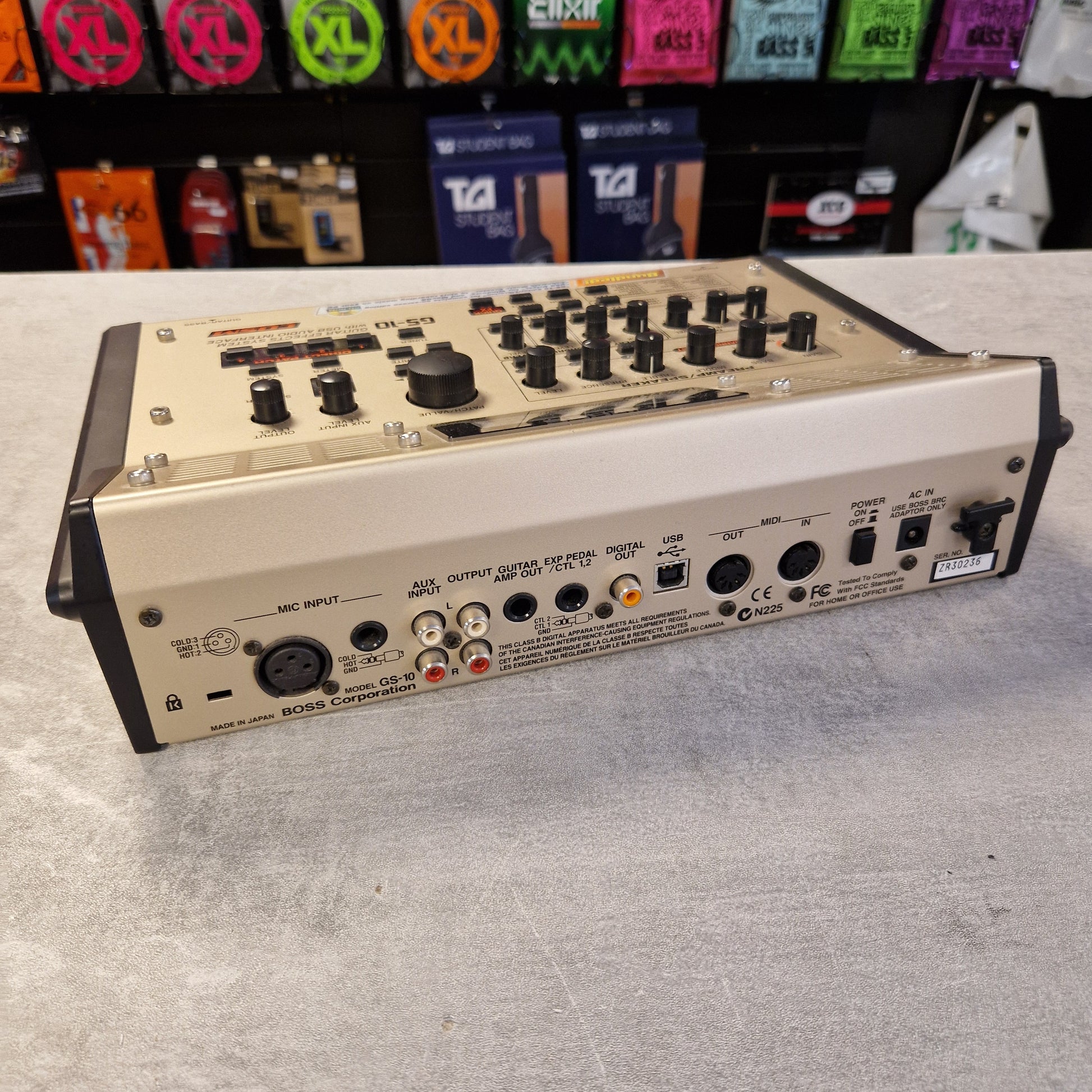 Pre-Owned Boss GS-10 Guitar effects pedal on a gray surface with colorful pedals in the background