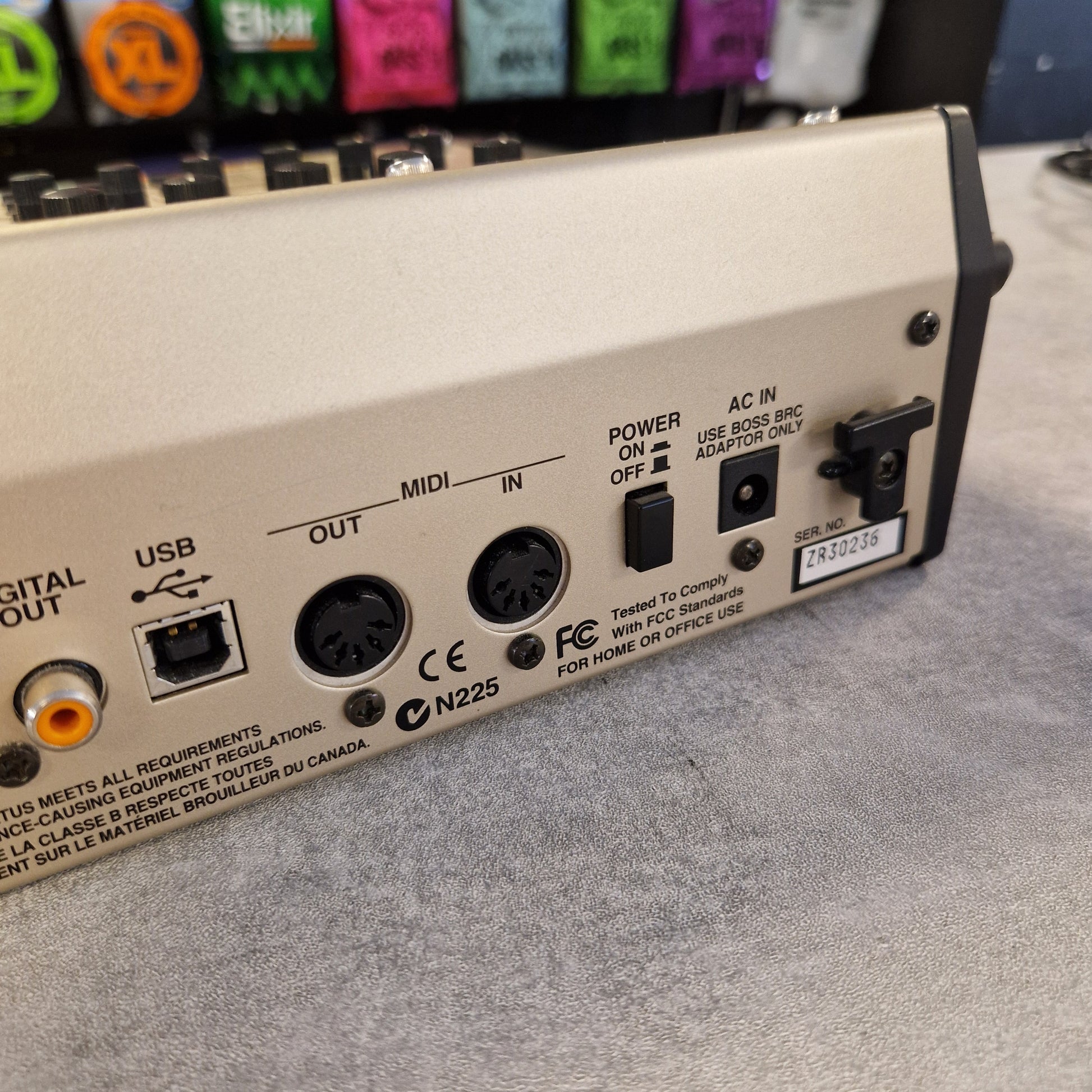 Pre-Owned Boss GS-10 Back panel of electronic equipment with various ports and labels on a gray surface