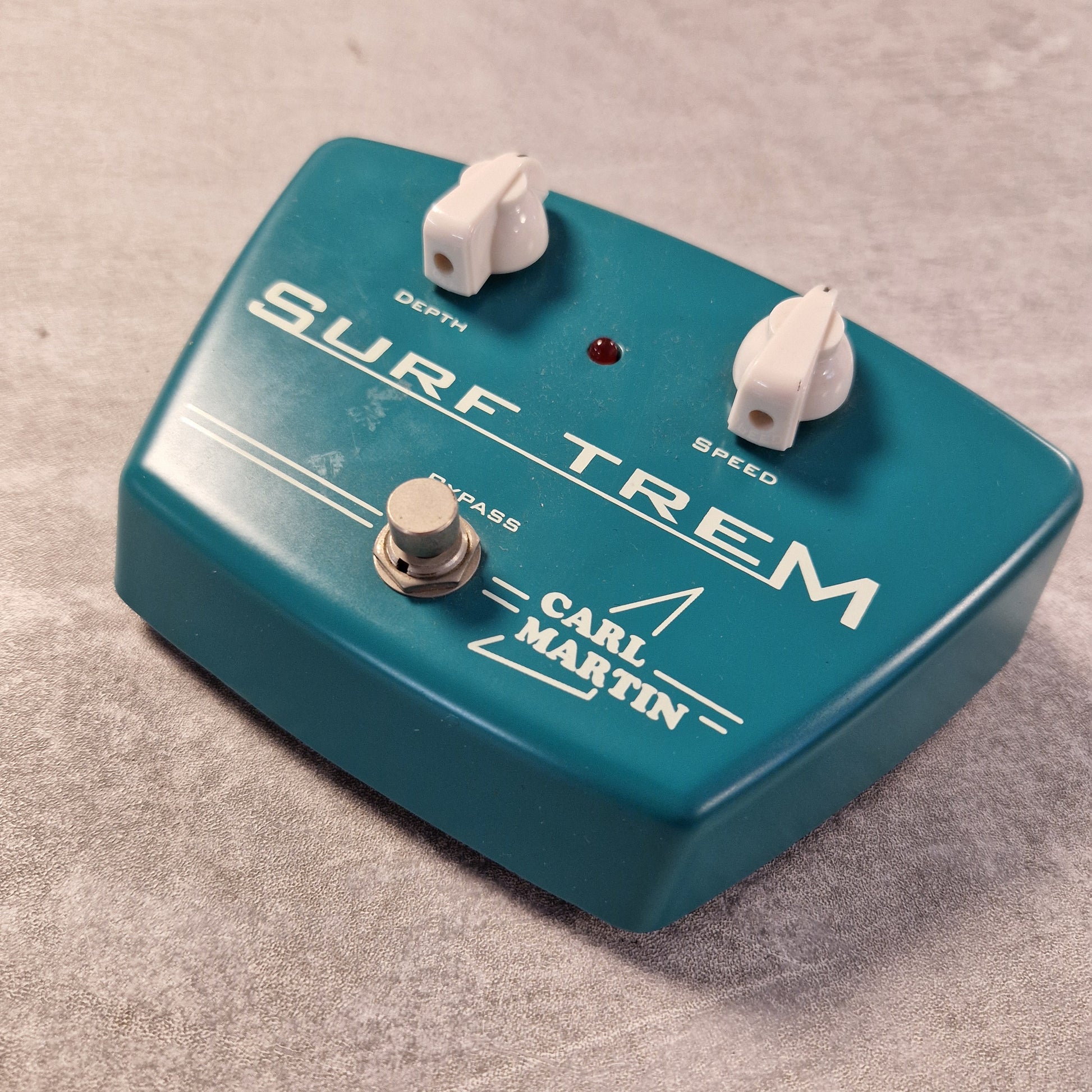 Pre-Owned Carl Martin Surf Trem Blue Carl Martin Surf Trem guitar effects pedal on a textured surface