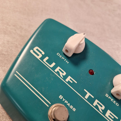 Pre-Owned Carl Martin Surf Trem Close-up of a teal guitar effects pedal with 'Surf Trem' branding.
