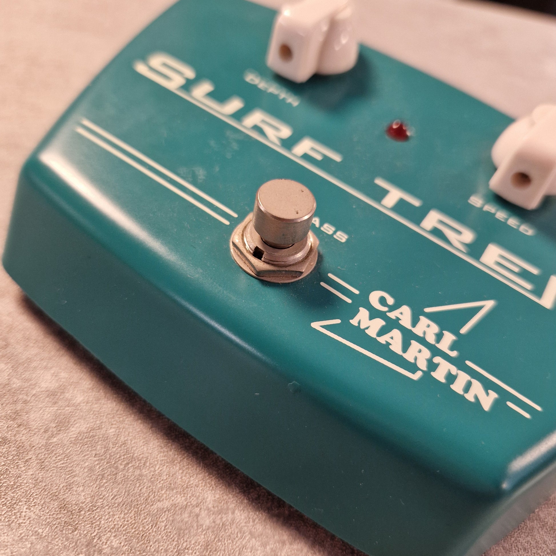 Pre-Owned Carl Martin Surf Trem Close-up of a teal Carl Martin guitar effects pedal with white text.