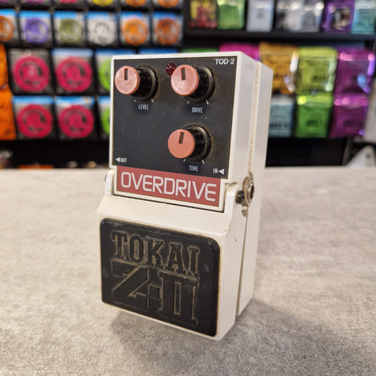 Pre-Owned Tokai Z-II TOD-2 Fender Overdrive guitar pedal on a gray surface with colorful boxes in the background