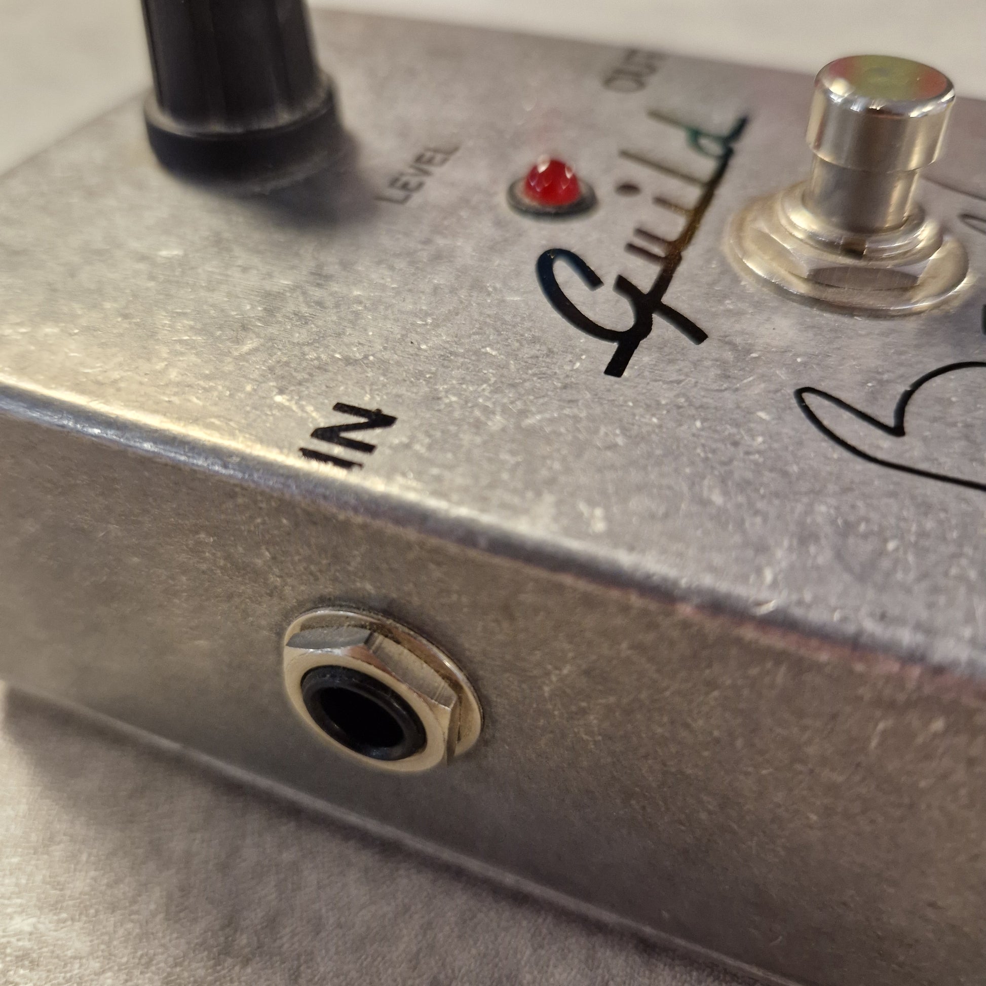 Pre-Owned Guild Brian May Close-up of a metallic electronic device with control knobs and labels.