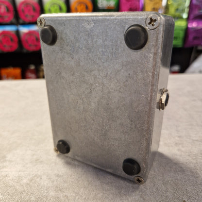 Pre-Owned Guild Brian May Metal box with screws on a gray surface with colorful objects in the background