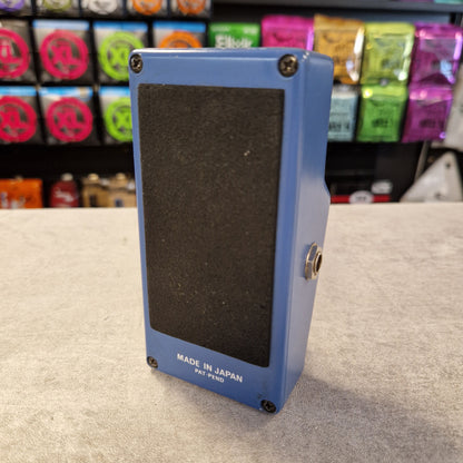 Pre-Owned Ibanez PT-999 Blue guitar effects pedal with 'Made in Japan' text on a gray surface, with colorful boxes in the background.