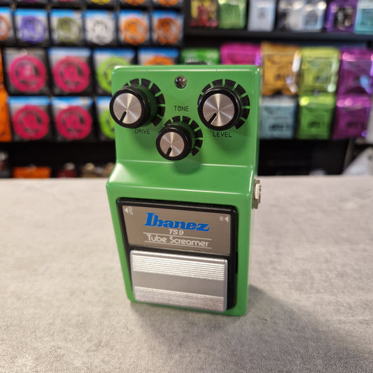 Pre-Owned Ibanez TS9 Green Ibanez effects pedal on a gray surface with colorful boxes in the background