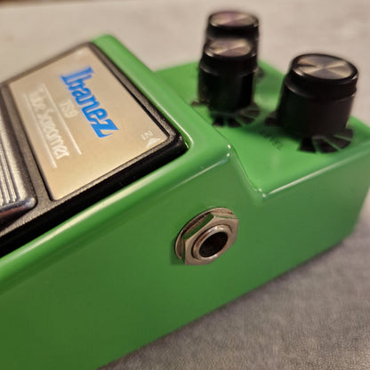 Pre-Owned Ibanez TS9 Close-up of a green Ibanez guitar effects pedal with two knobs on a gray background.