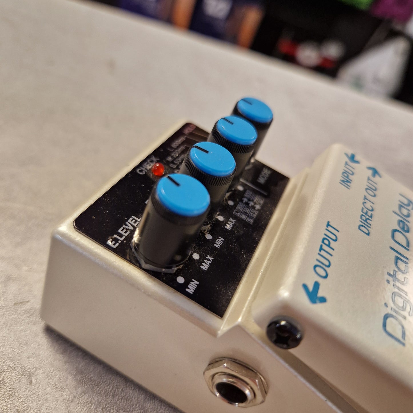 Pre-Owned Boss DD-3 Gibson digital delay guitar effects pedal with blue knobs on a blurred background