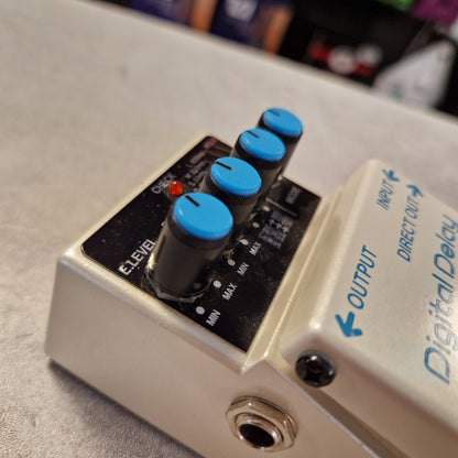 Pre-Owned Boss DD-3 Gibson digital delay guitar effects pedal with blue knobs on a blurred background