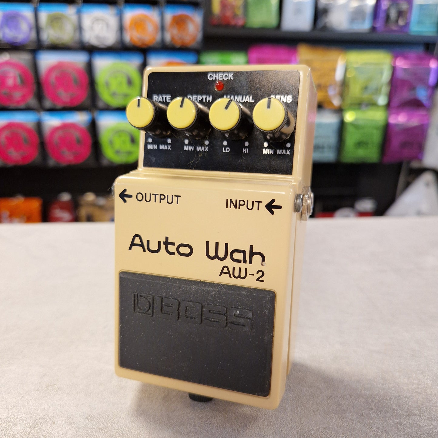 Pre-Owned Boss AW-2 Boss Auto Wah AW-2 guitar effects pedal on a gray surface with a colorful background.