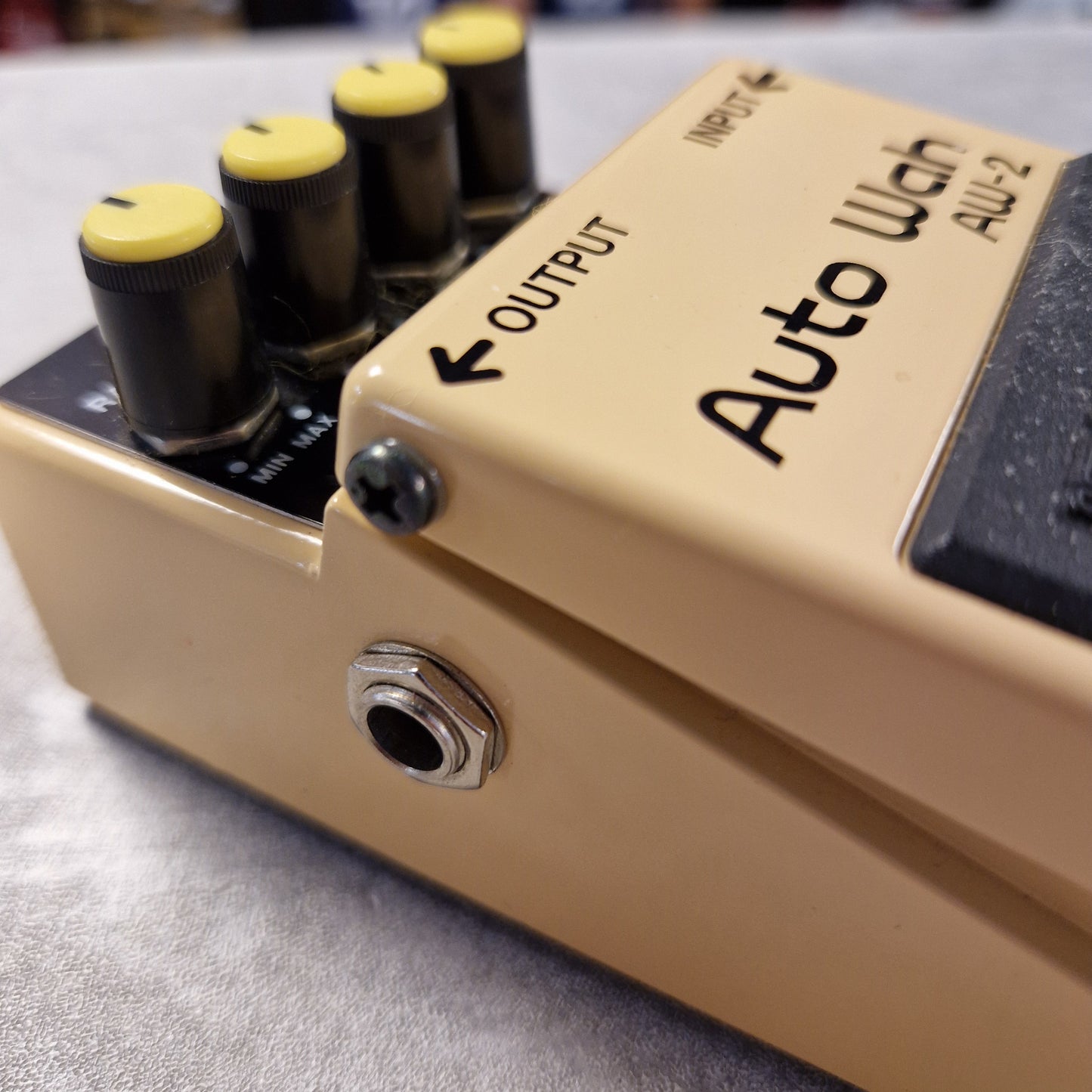 Pre-Owned Boss AW-2 Close-up of a guitar effects pedal with 'Auto Wah' branding on a gray surface.