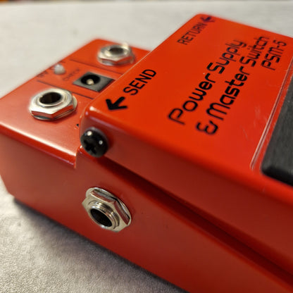 Pre-Owned Boss PSM-5 Close-up of a red electronic pedal with labeled ports on a metallic surface.