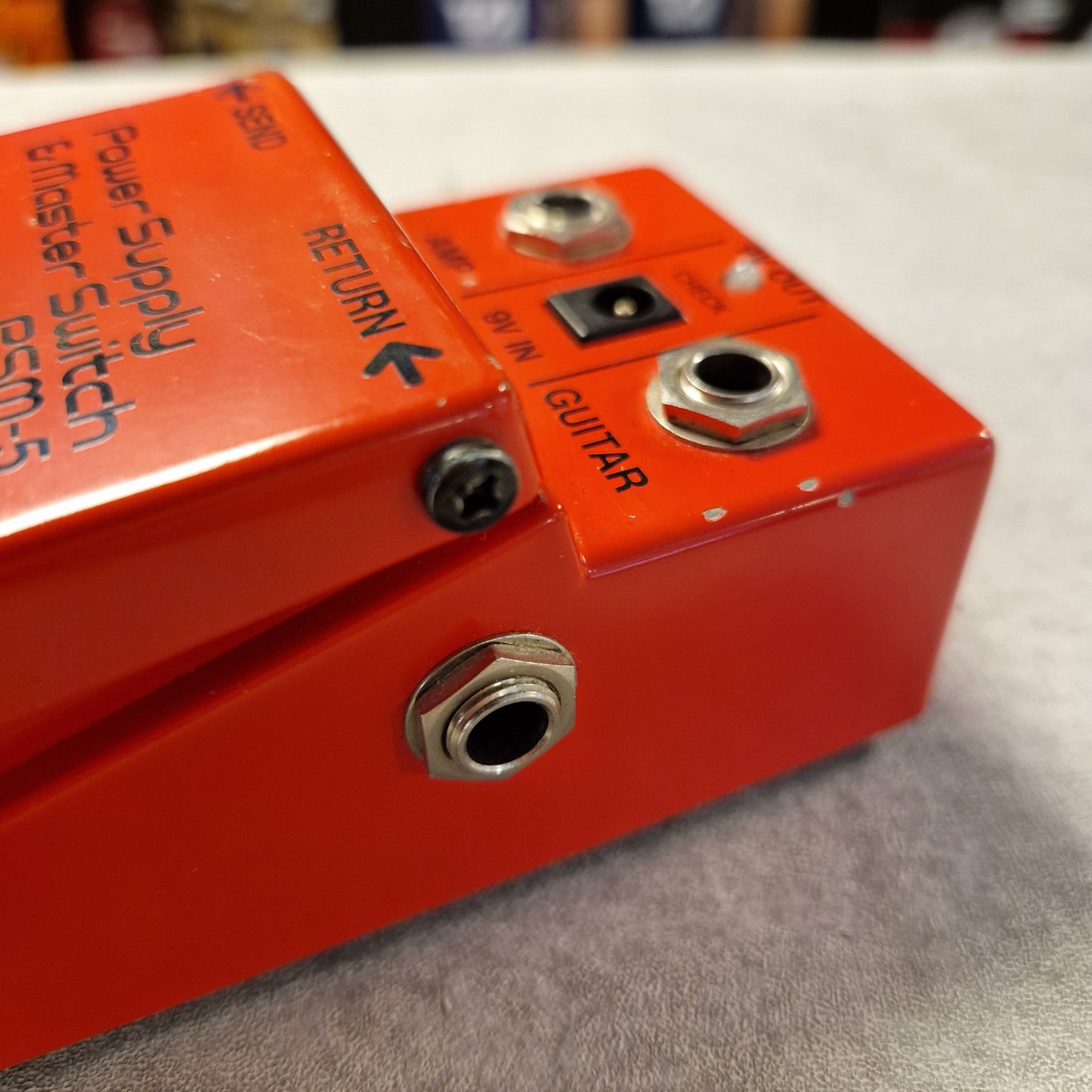 Pre-Owned Boss PSM-5 Red guitar effects pedal with visible labels on a blurred background