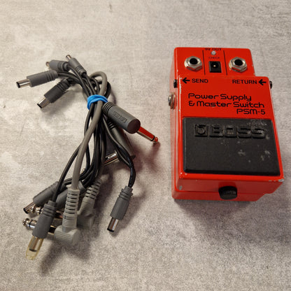 Pre-Owned Boss PSM-5 Red power supply switch with multiple cables on a gray surface