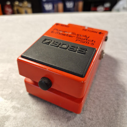Pre-Owned Boss PSM-5 Red BOSS guitar pedal on a gray surface with blurred background