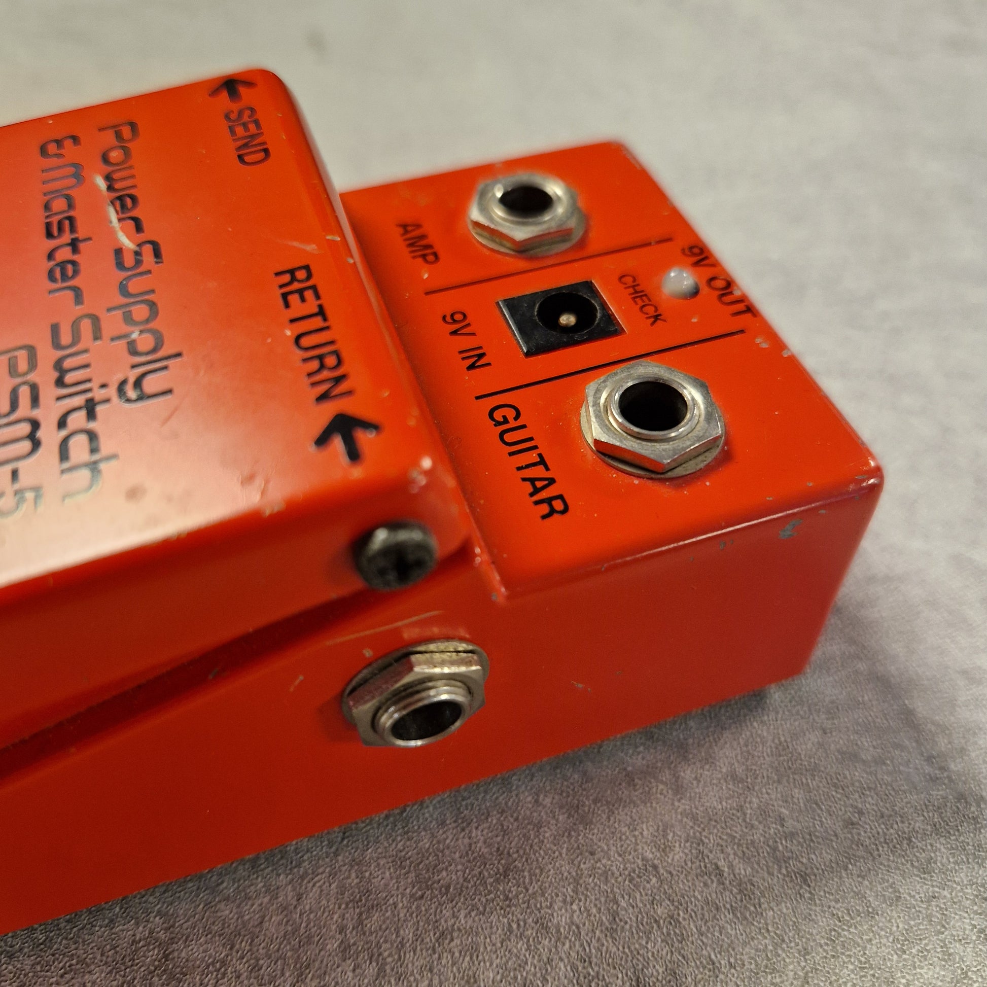 Pre-Owned Boss PSM-5 Red power supply and master switch pedal with labeled ports on a gray background