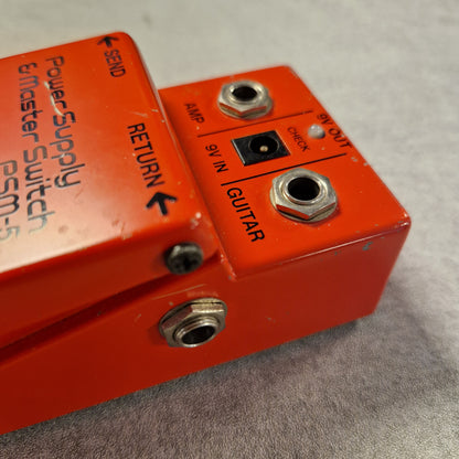 Pre-Owned Boss PSM-5 Red power supply and master switch pedal with labeled ports on a gray background