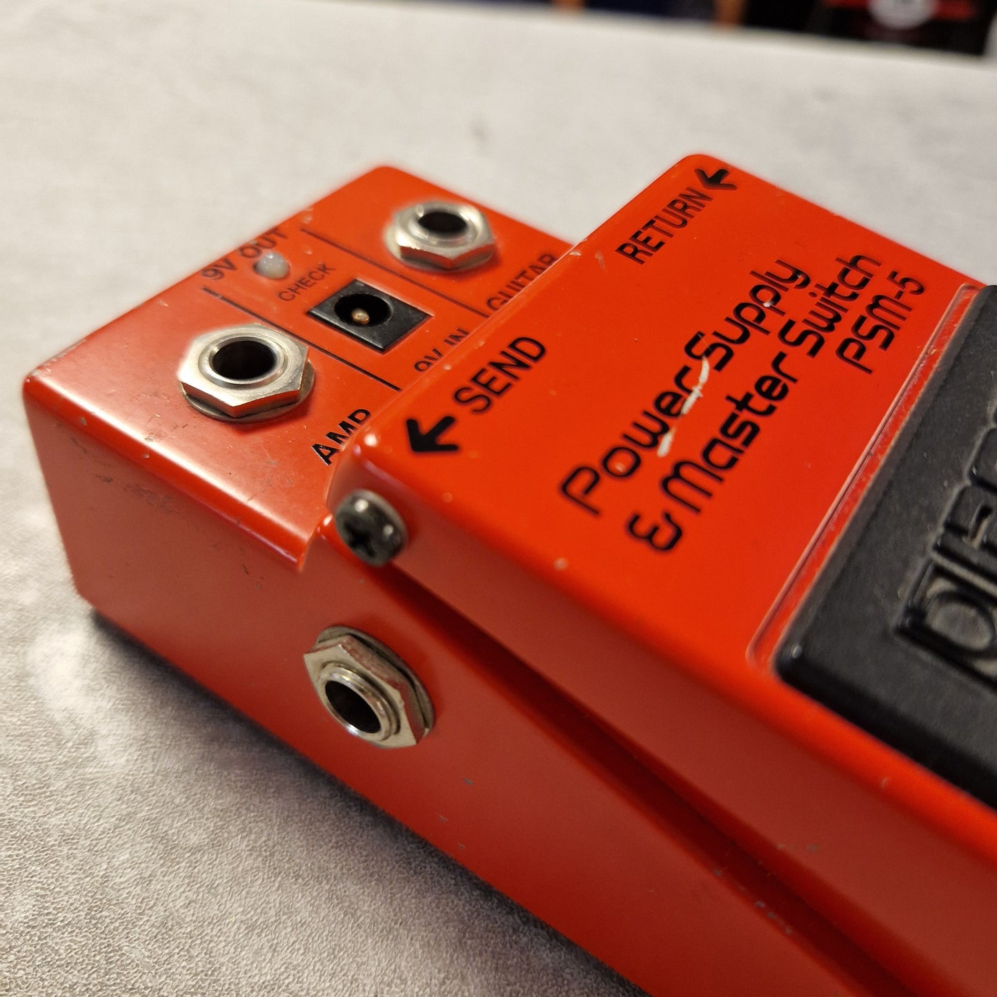 Pre-Owned Boss PSM-5 Close-up of a red electronic pedal with labels and connectors on a gray surface