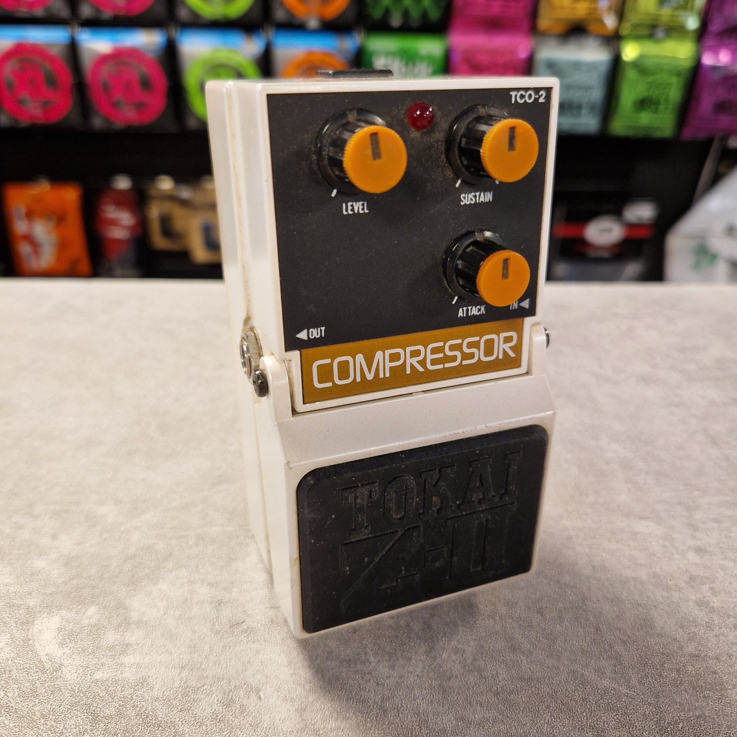 Pre-Owned Tokai Z-II TCO-2 Compressor guitar effects pedal on a gray surface with colorful boxes in the background