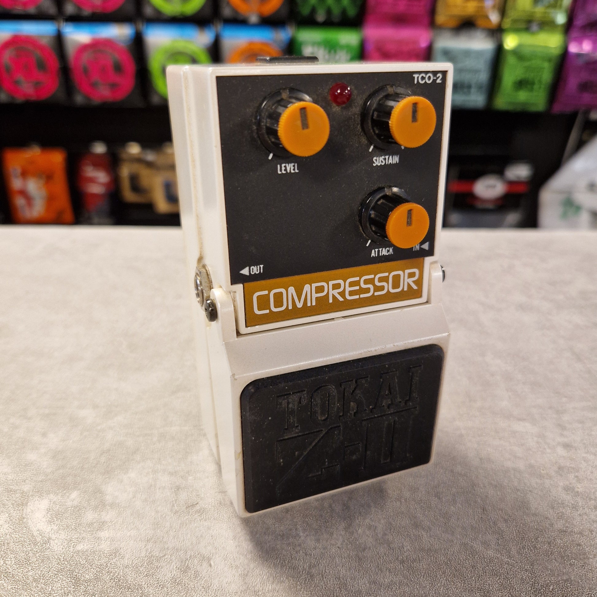 Pre-Owned Tokai Z-II TCO-2 Compressor guitar effects pedal on a gray surface with colorful boxes in the background