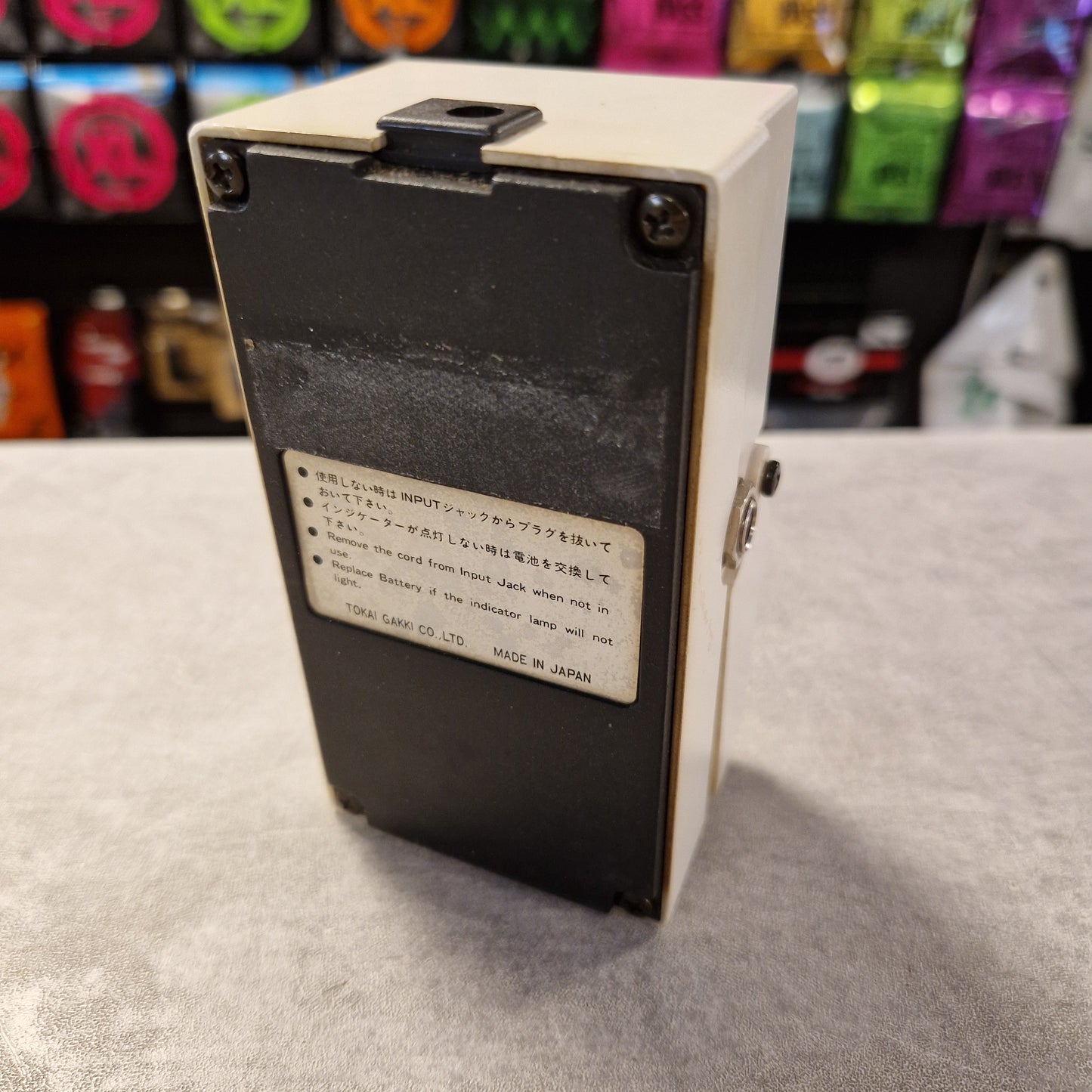 Pre-Owned Tokai Z-II TCO-2 Small electronic device with a label on a gray surface, colorful items in the background