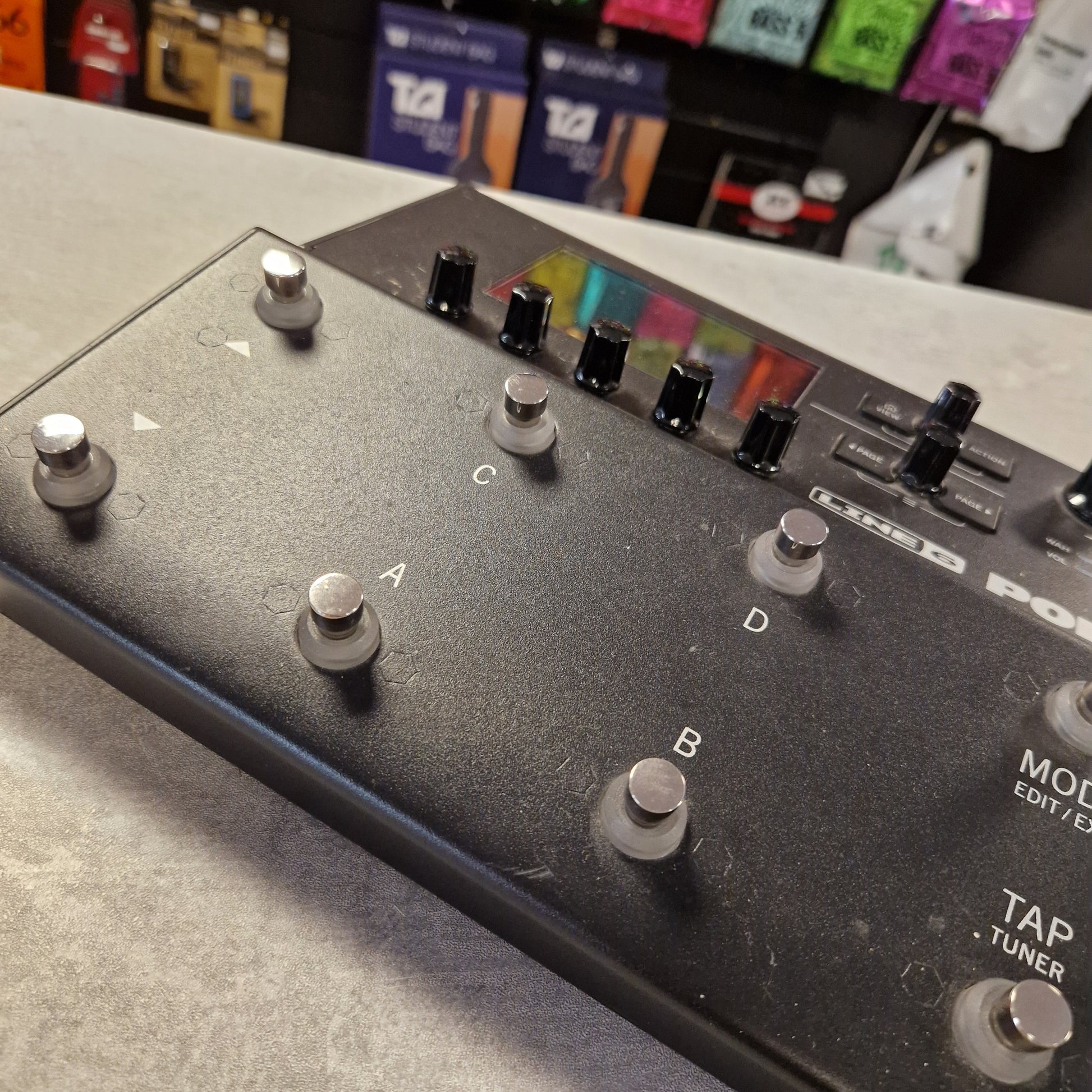 Pre-Owned Line 6 POD Go Close-up of a guitar effects pedal with control knobs and buttons on a gray surface.