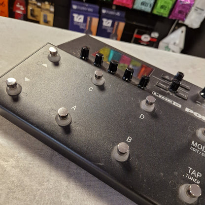 Pre-Owned Line 6 POD Go Close-up of a guitar effects pedal with control knobs and buttons on a gray surface.