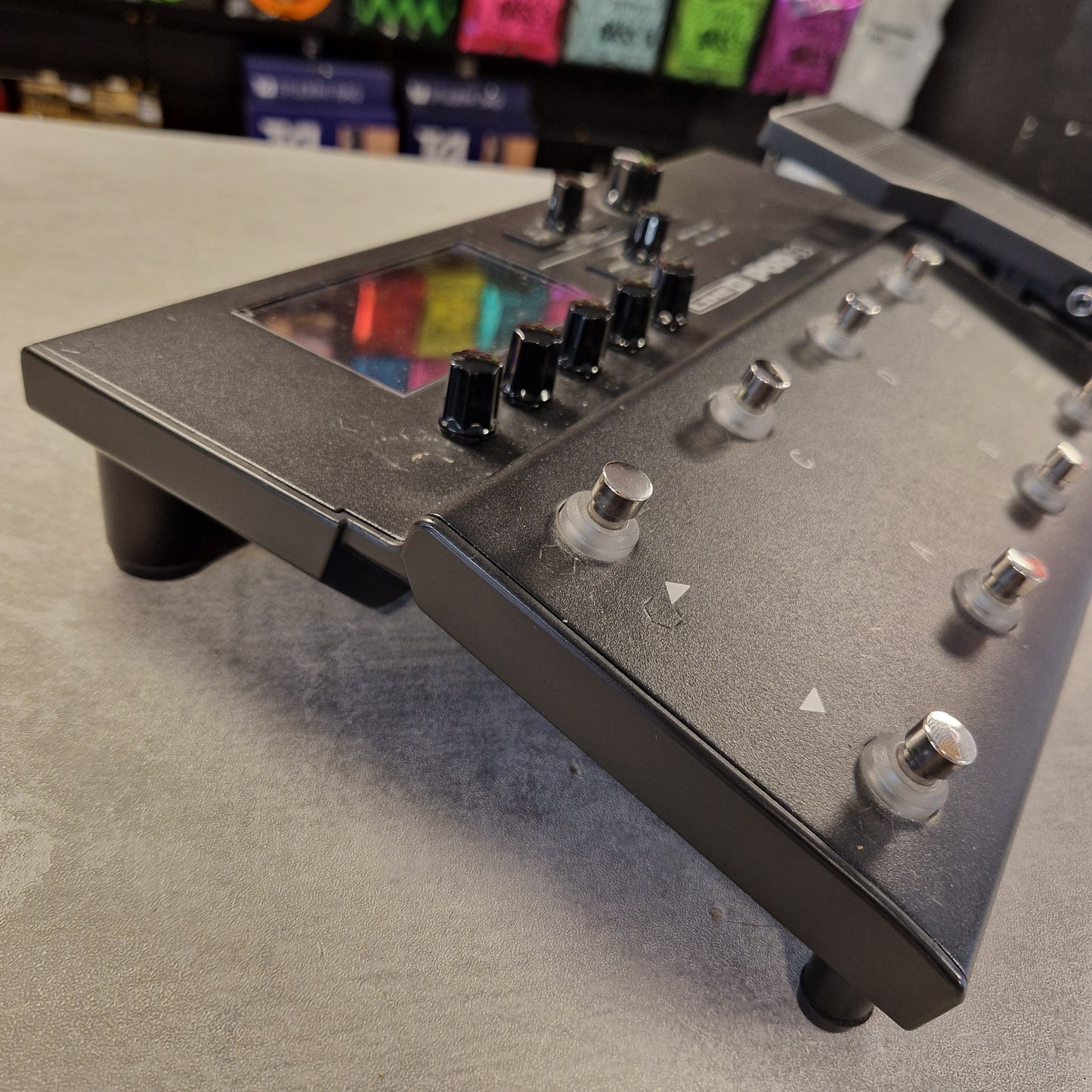 Pre-Owned Line 6 POD Go Close-up of a guitar effects pedal with colorful knobs on a gray surface.