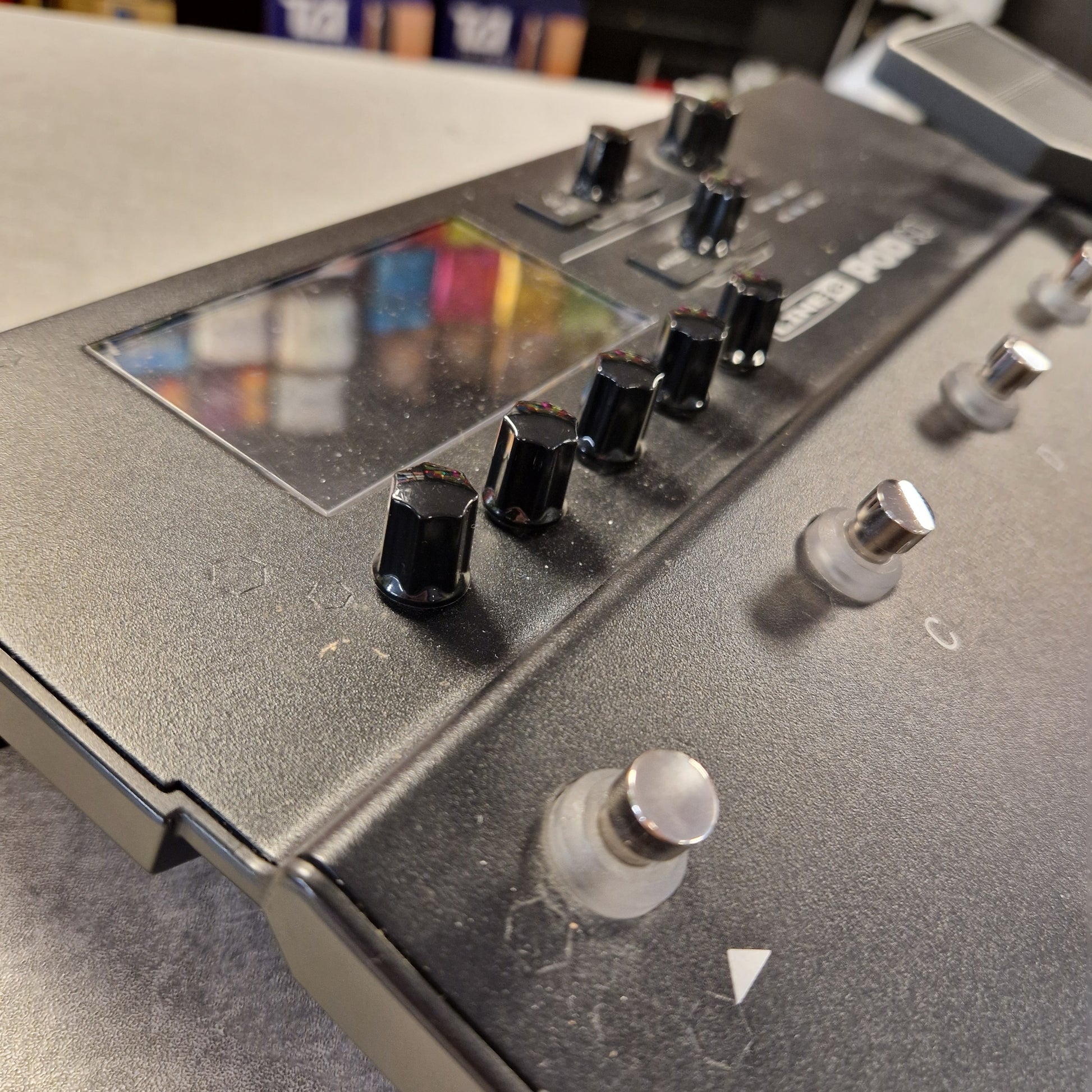 Pre-Owned Line 6 POD Go Close-up of a metallic control panel with knobs and a color swatch on a blurred background