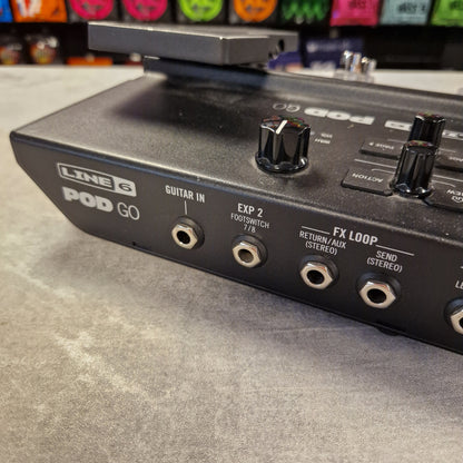 Pre-Owned Line 6 POD Go Line 6 Pod Go guitar effects processor on a gray surface with colorful pedals in the background.