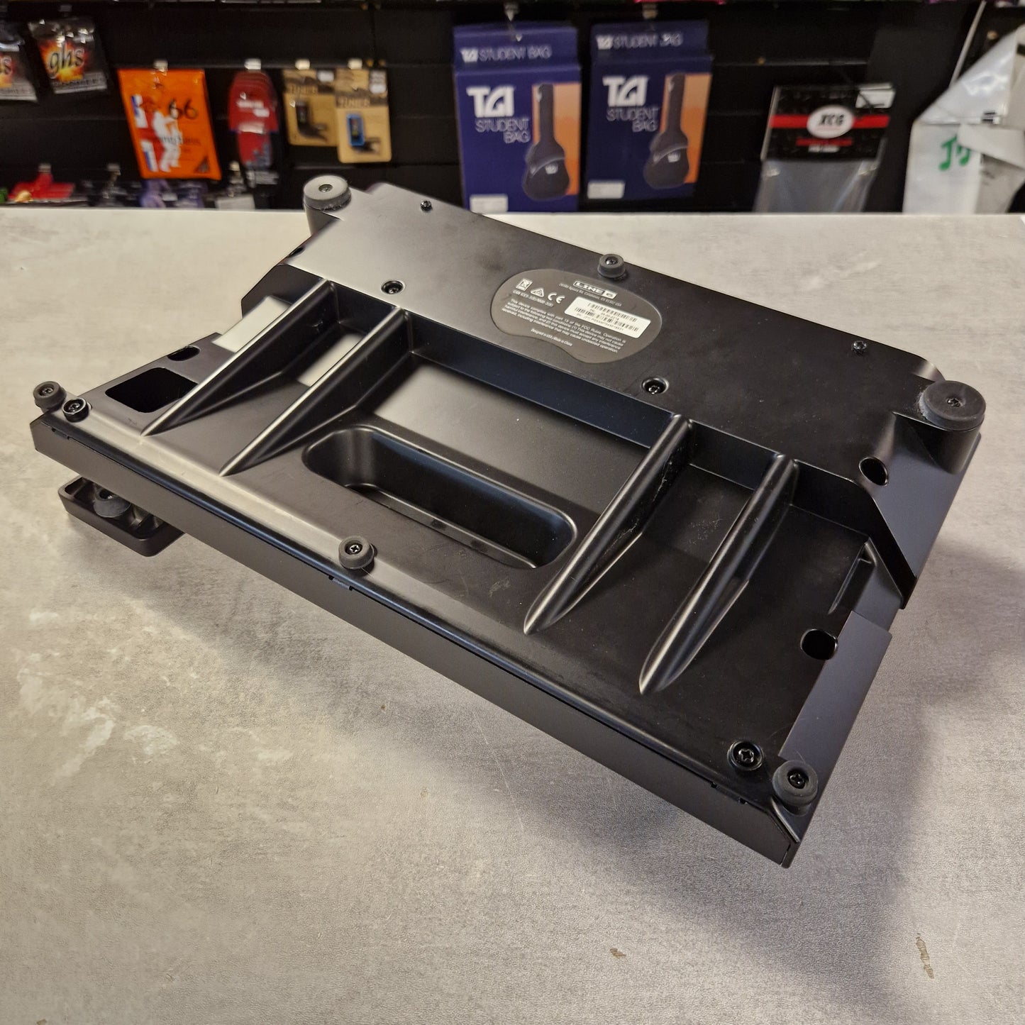 Pre-Owned Line 6 POD Go Black metal bracket on a gray surface with a blurred background