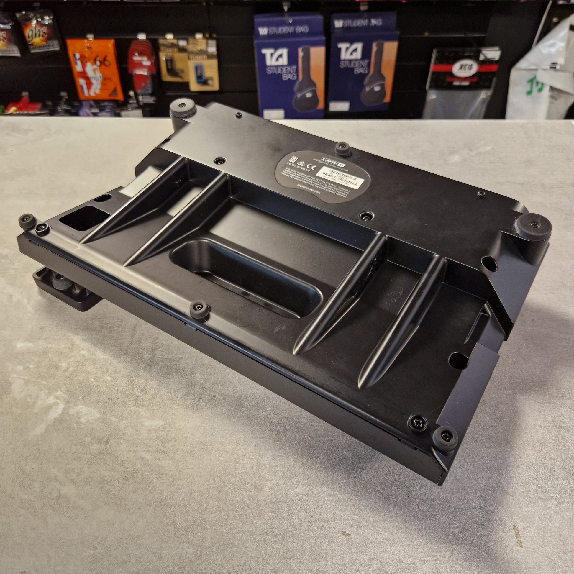 Pre-Owned Line 6 POD Go Black metal bracket on a gray surface with a blurred background