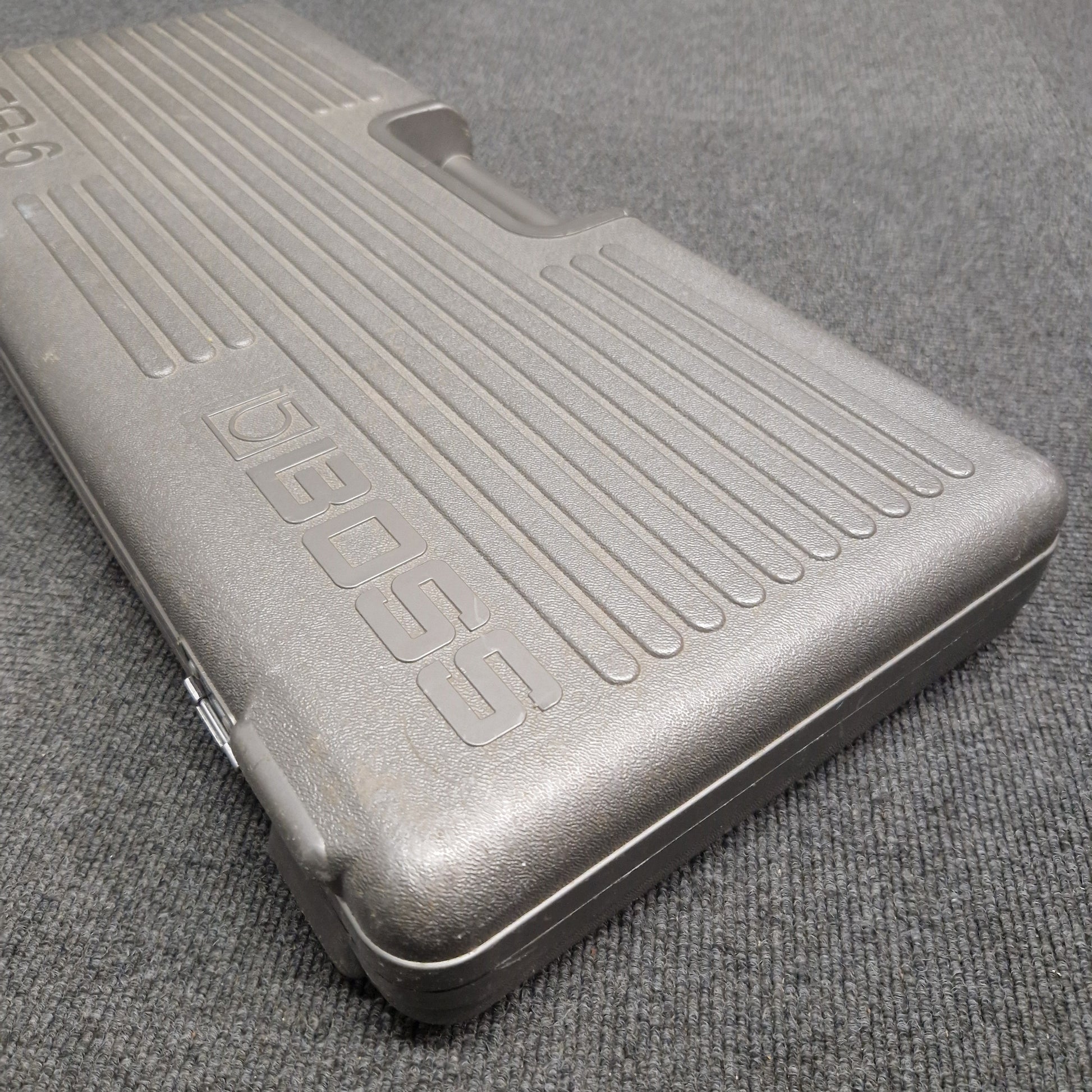 Pre-Owned Boss BCB-6 Metallic case with 'BOSS' branding on a textured gray surface