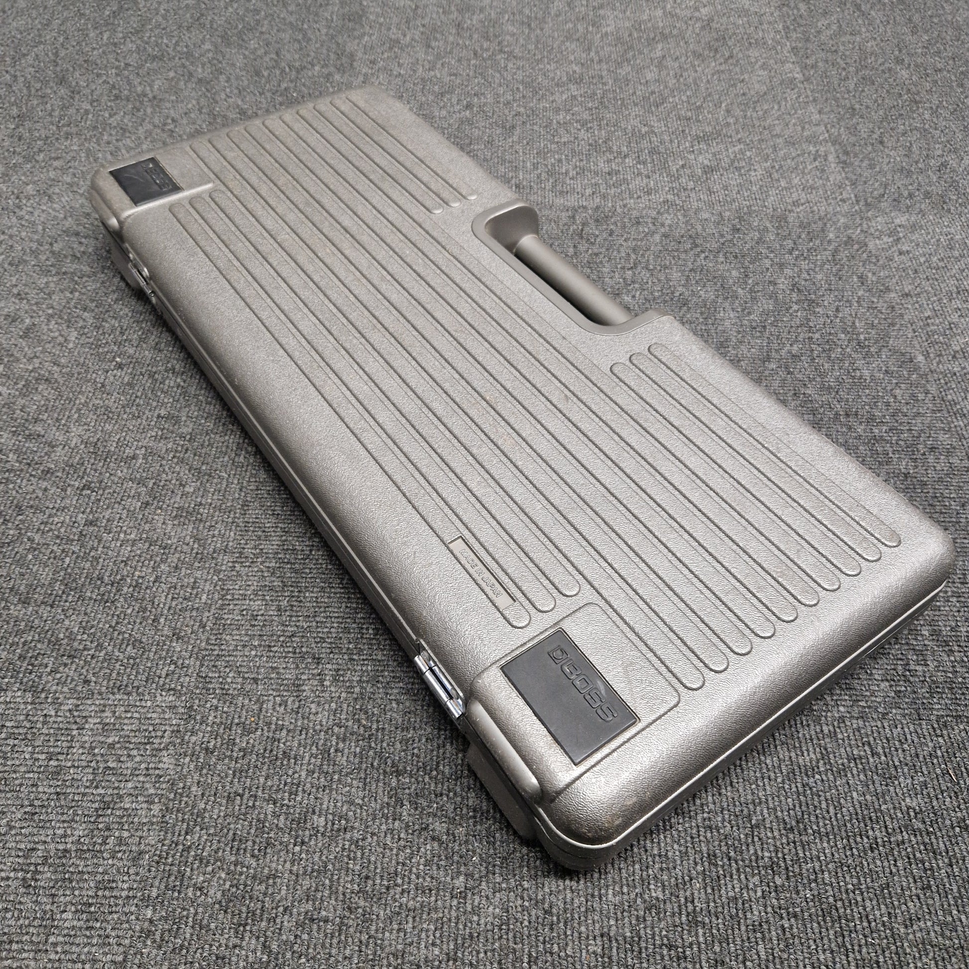Pre-Owned Boss BCB-6 Silver metallic case on a textured gray surface
