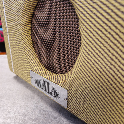 Pre-Owned Kala AMP-TWD Close-up of a guitar with a Kala brand label on a striped background