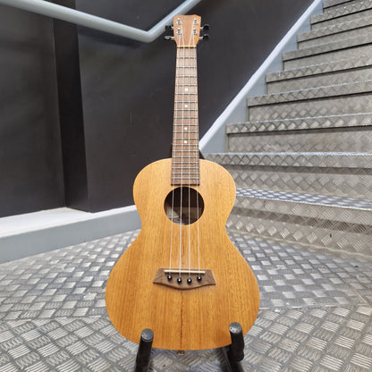 Pre-Owned Islander by Kanilea MT-4 Small wooden guitar leaning against a textured wall.