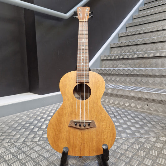 Pre-Owned Islander by Kanilea MT-4 Small wooden guitar leaning against a textured wall.