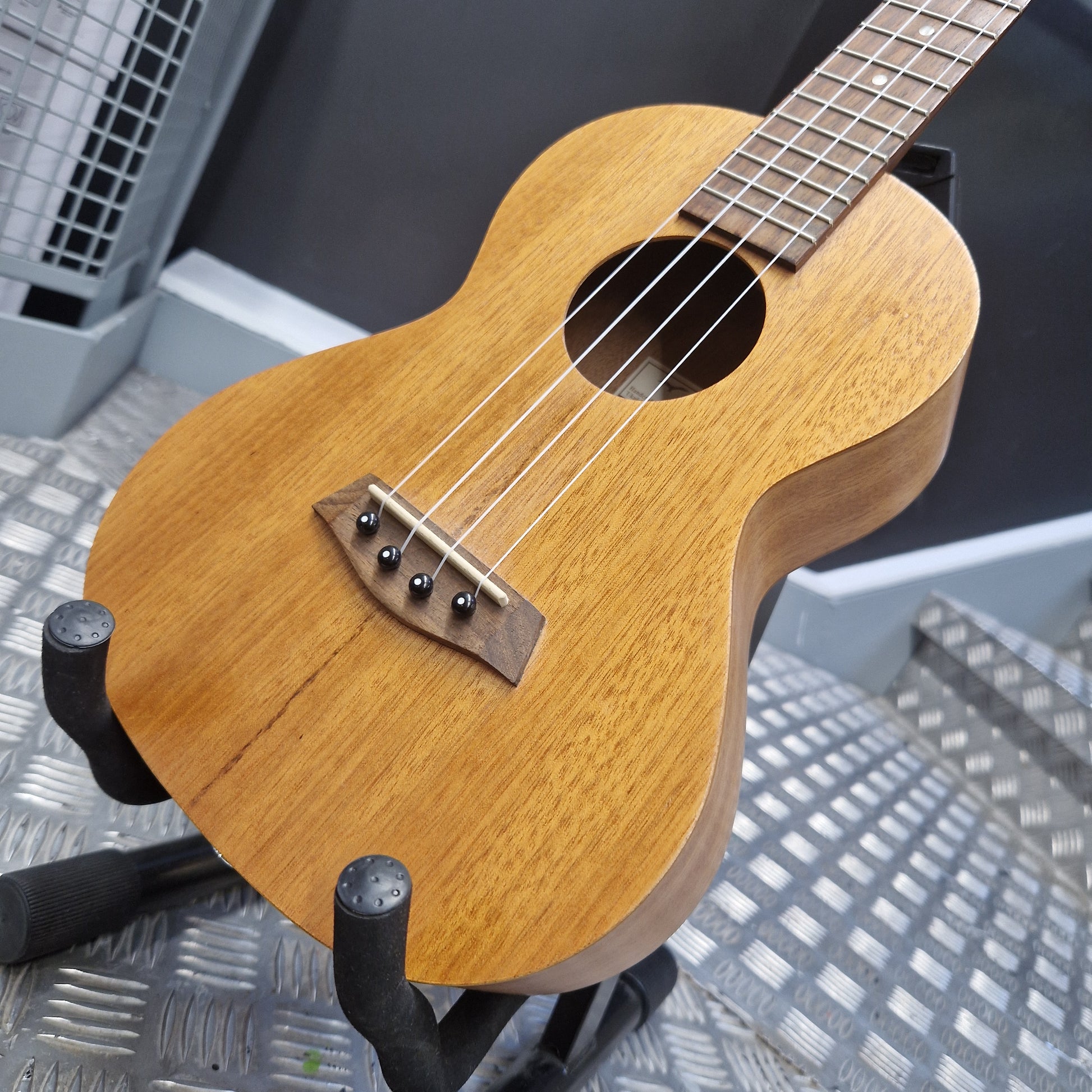 Pre-Owned Islander by Kanilea MT-4 Wooden ukulele on a stand with a metallic background