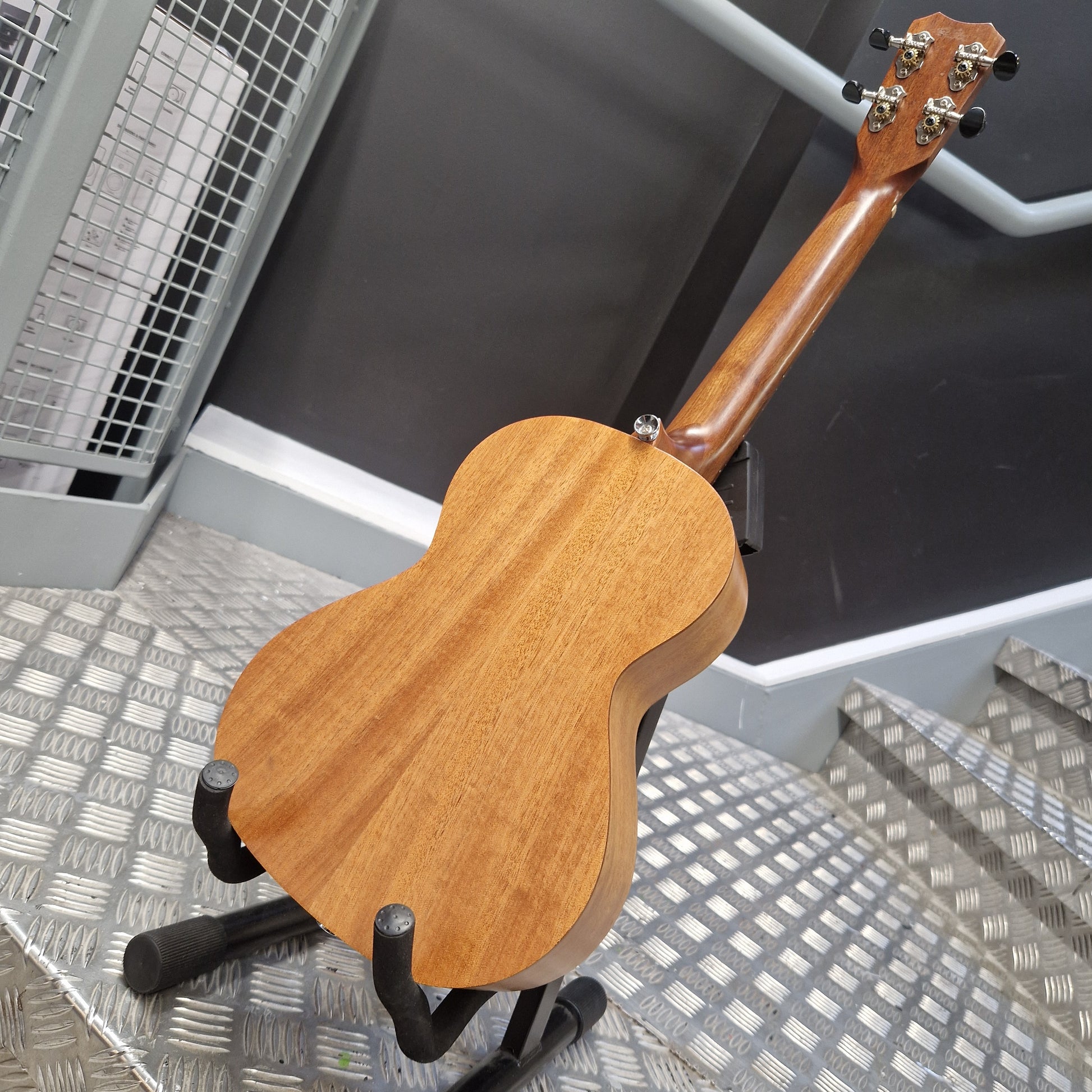 Pre-Owned Islander by Kanilea MT-4 Wooden guitar headstock and neck on a stand with a metal floor and wall in the background