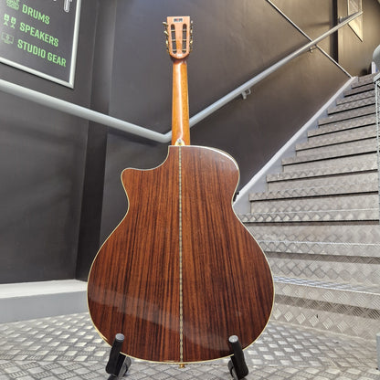Pre-Owned Crafter TMC035/N Wooden acoustic guitar on a stand in an indoor setting with stairs and wall.