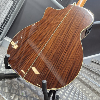 Pre-Owned Crafter TMC035/N Close-up of a wooden acoustic guitar on a stand with a blurred background