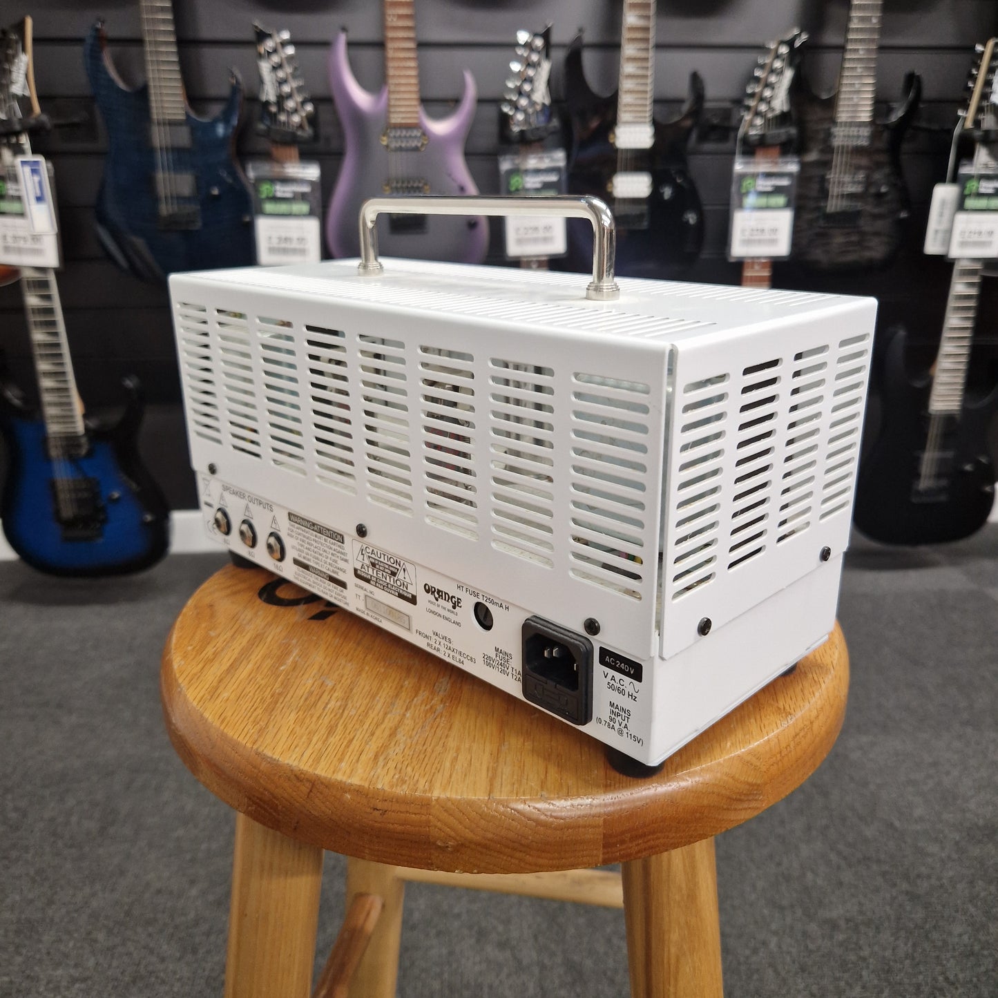 Pre-Owned Orange TT15H White guitar amplifier on a wooden stand with guitars in the background