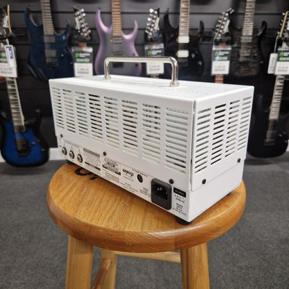 Pre-Owned Orange TT15H White guitar amplifier on a wooden stand with guitars in the background