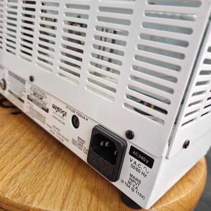 Pre-Owned Orange TT15H Back of a white electronic device with power connector on a wooden surface